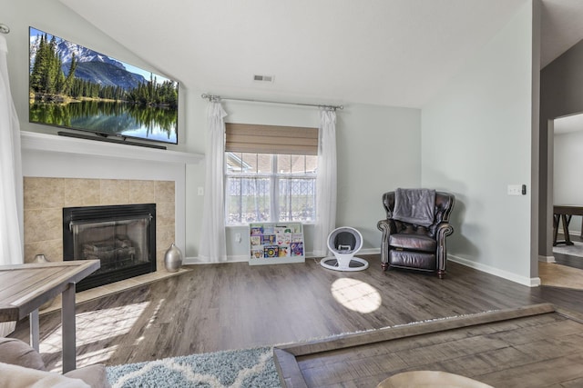 living room featuring wood-type flooring, a fireplace, and vaulted ceiling