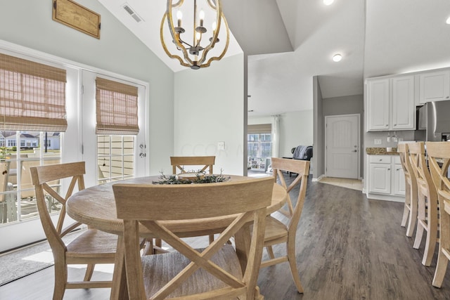 dining area featuring high vaulted ceiling, dark wood-type flooring, and an inviting chandelier