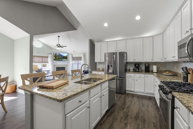 kitchen featuring stainless steel appliances, a kitchen island with sink, sink, white cabinets, and lofted ceiling