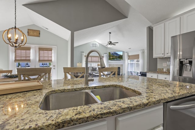 kitchen featuring ceiling fan with notable chandelier, sink, stone countertops, white cabinetry, and lofted ceiling