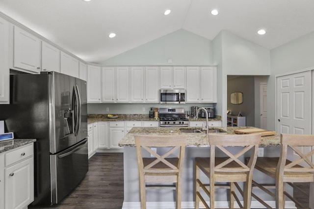 kitchen featuring dark wood-type flooring, sink, appliances with stainless steel finishes, white cabinetry, and a breakfast bar area