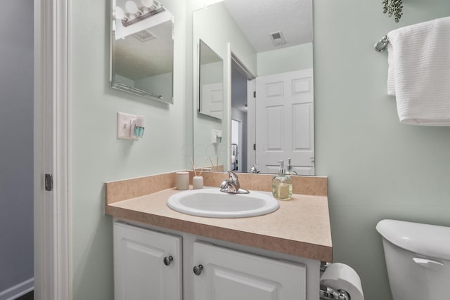 bathroom with vanity, a textured ceiling, and toilet