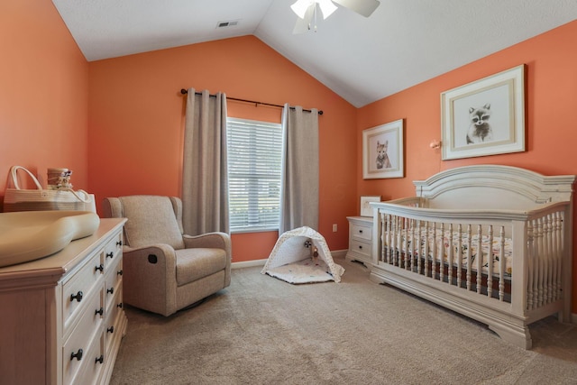 carpeted bedroom with ceiling fan, a nursery area, and lofted ceiling