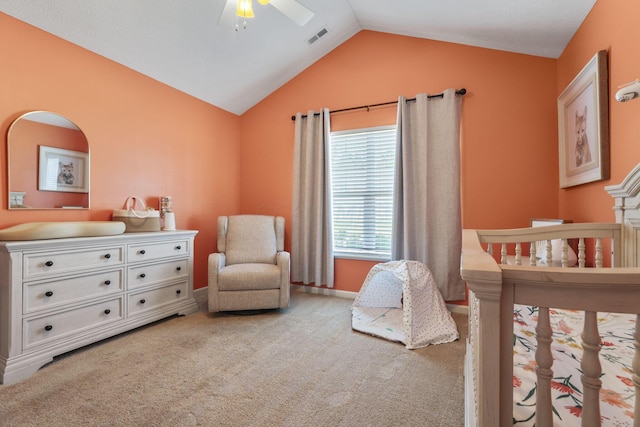 bedroom with ceiling fan, light colored carpet, a crib, and vaulted ceiling