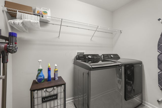 clothes washing area with separate washer and dryer and a textured ceiling