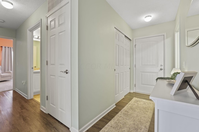 hallway with a textured ceiling and dark hardwood / wood-style floors