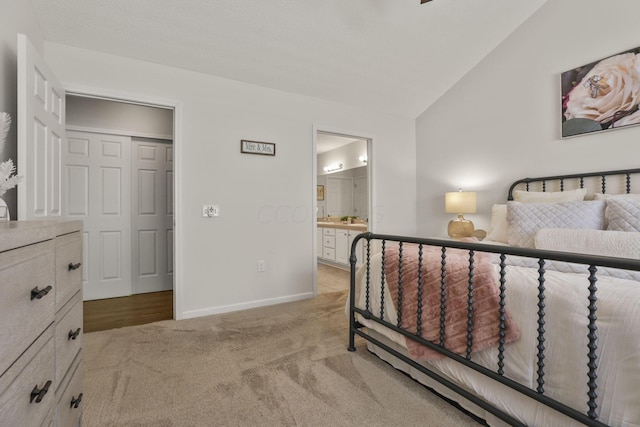 carpeted bedroom with ensuite bathroom and lofted ceiling