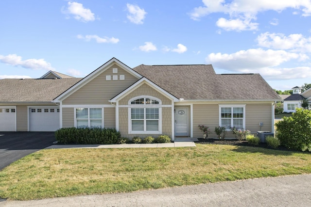 view of front of home with central air condition unit, a front yard, and a garage