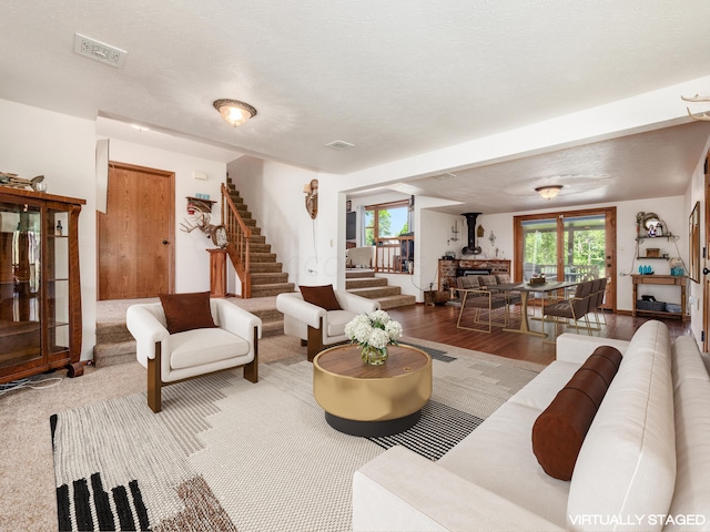 living room with a textured ceiling, hardwood / wood-style flooring, and a wood stove