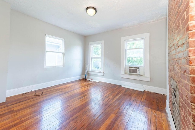 empty room with dark hardwood / wood-style flooring, plenty of natural light, and cooling unit