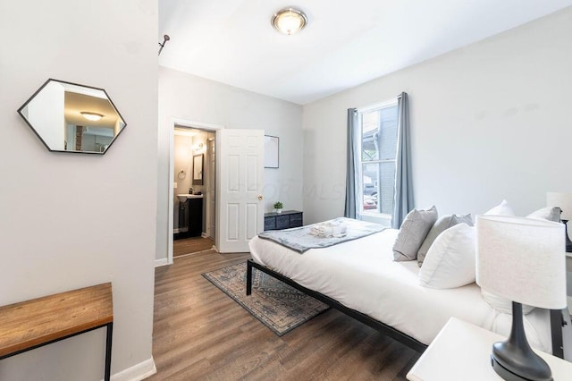 bedroom with ensuite bath and hardwood / wood-style flooring