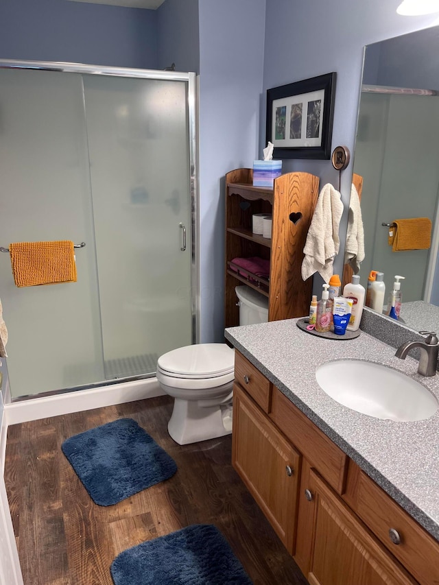 bathroom with toilet, vanity, a shower with shower door, and hardwood / wood-style flooring