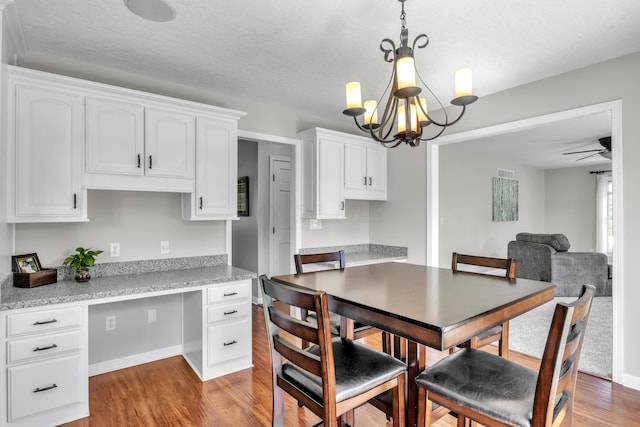 dining space featuring ceiling fan with notable chandelier, a textured ceiling, and light hardwood / wood-style flooring