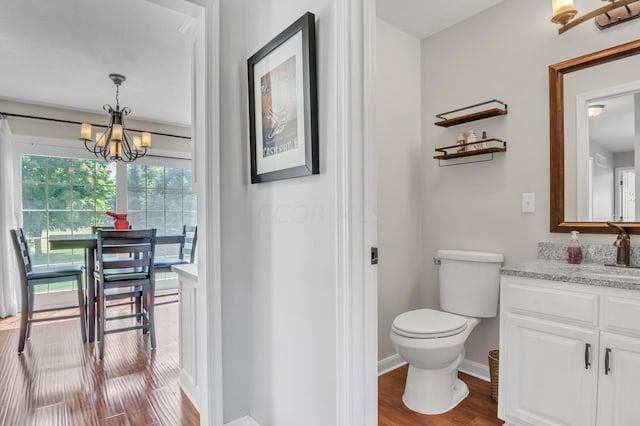 bathroom with hardwood / wood-style floors, vanity, toilet, and a chandelier