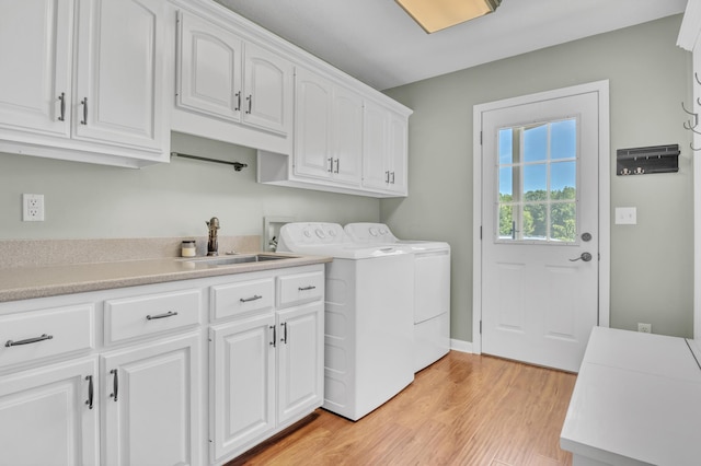 washroom with cabinets, washing machine and dryer, light hardwood / wood-style flooring, and sink