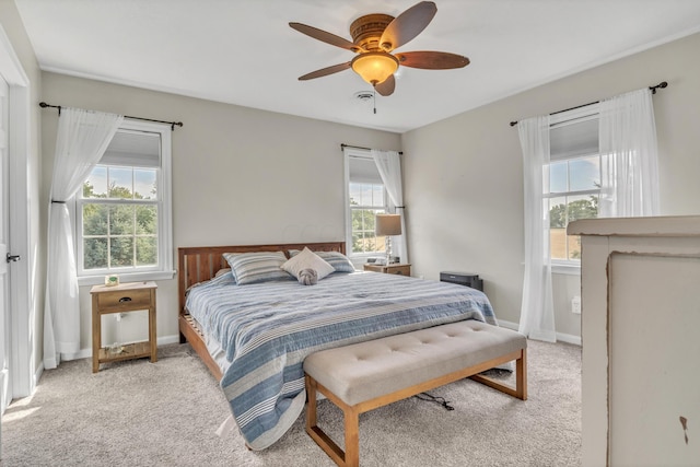 bedroom featuring ceiling fan, light carpet, and multiple windows