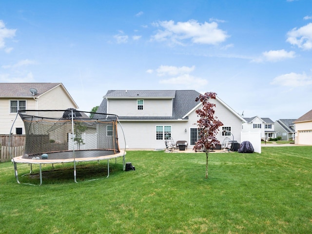 back of property featuring a yard and a trampoline