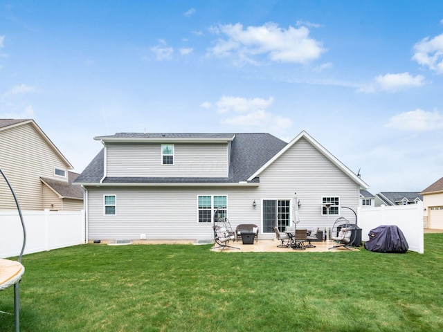 back of house featuring a lawn, a patio, and a trampoline