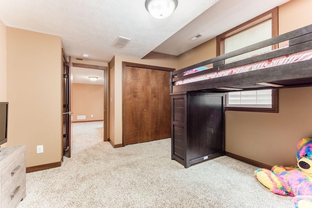 unfurnished bedroom with light carpet, a closet, and a textured ceiling