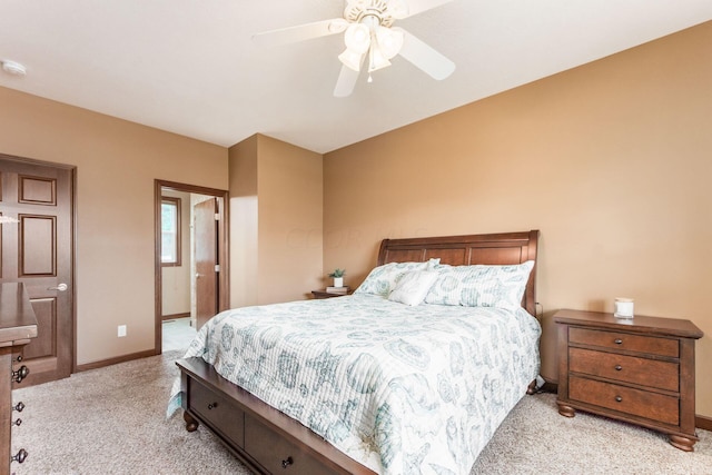 bedroom with ceiling fan, light colored carpet, and ensuite bathroom