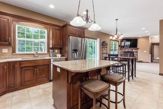 kitchen featuring a center island, sink, a fireplace, stainless steel appliances, and a chandelier