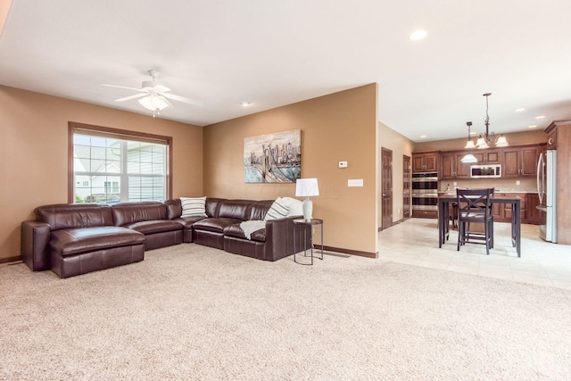 carpeted living room featuring ceiling fan with notable chandelier