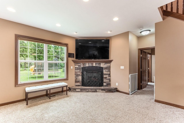 carpeted living room featuring a stone fireplace