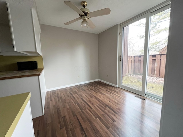 unfurnished dining area with dark hardwood / wood-style flooring and ceiling fan