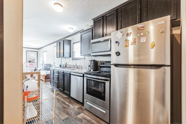 kitchen with dark wood-type flooring, sink, a textured ceiling, dark brown cabinets, and stainless steel appliances