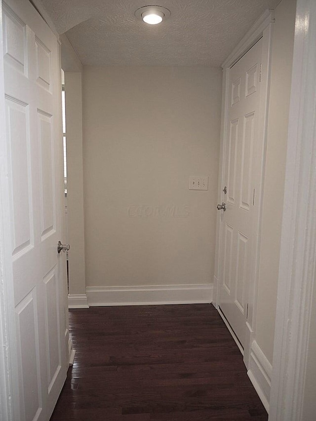 hallway featuring a textured ceiling and dark hardwood / wood-style floors