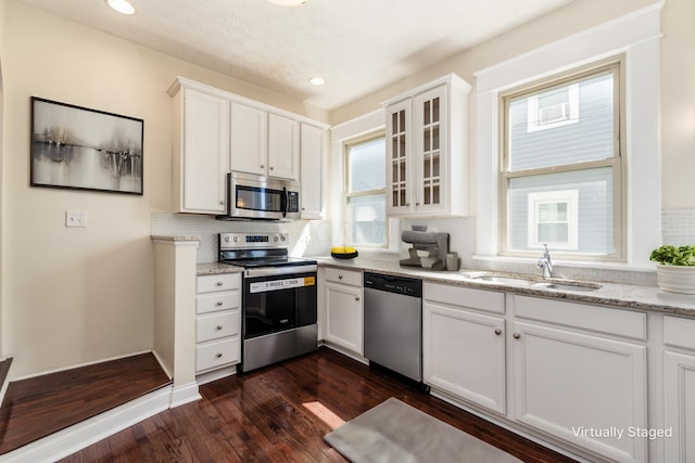 kitchen featuring sink, white cabinetry, light stone countertops, dark hardwood / wood-style flooring, and appliances with stainless steel finishes