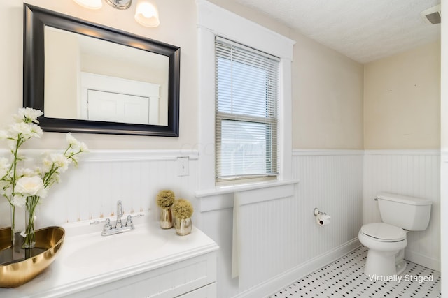 bathroom with a textured ceiling, tile patterned flooring, vanity, and toilet