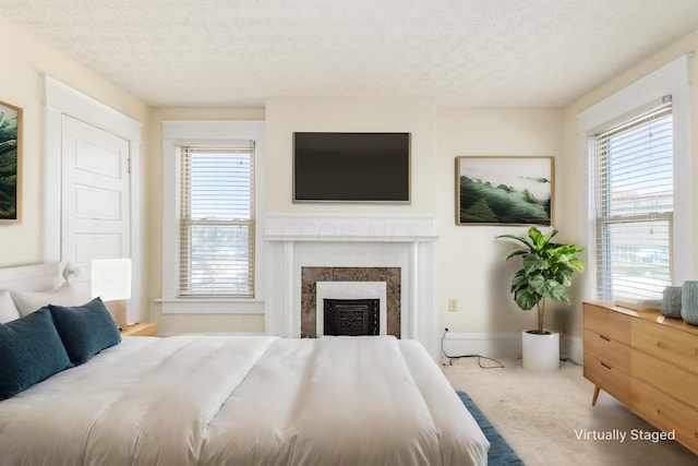 carpeted bedroom featuring a fireplace, a textured ceiling, and multiple windows