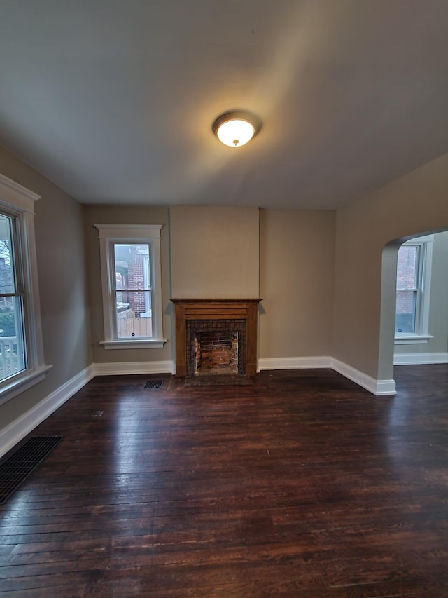 unfurnished living room featuring dark hardwood / wood-style floors and a tiled fireplace