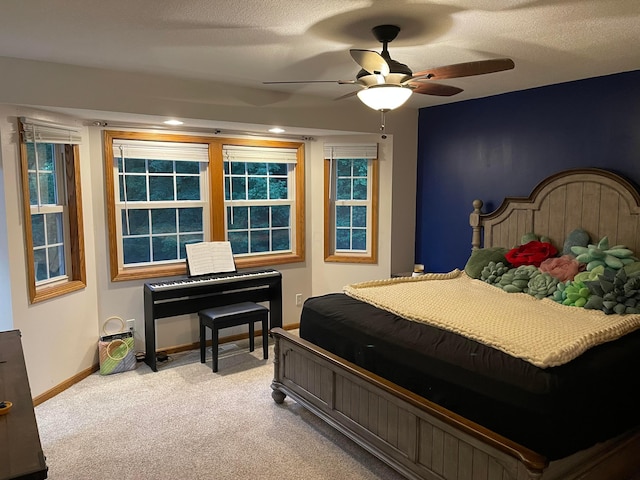 carpeted bedroom featuring ceiling fan, a textured ceiling, and multiple windows