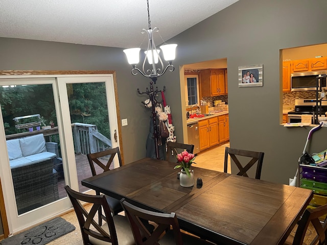 dining area with a textured ceiling, a chandelier, sink, and vaulted ceiling