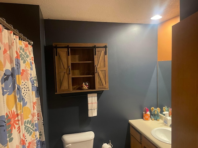 bathroom featuring vanity, a textured ceiling, and toilet