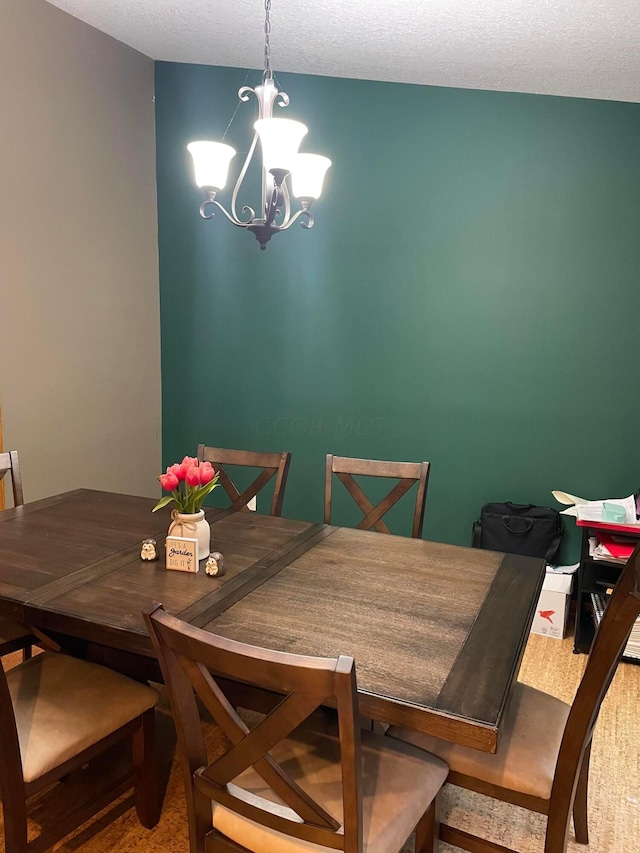 carpeted dining space featuring a textured ceiling and a notable chandelier