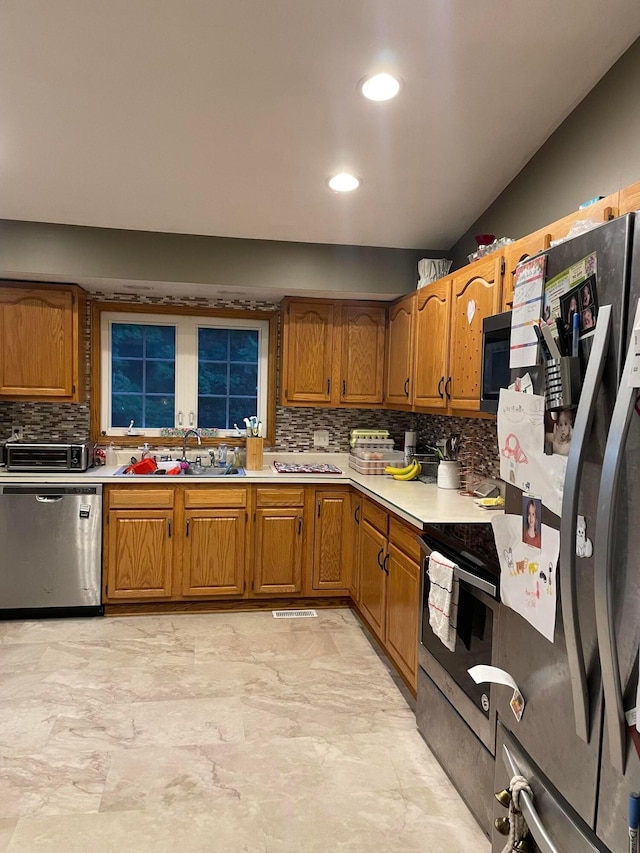 kitchen featuring backsplash, sink, and appliances with stainless steel finishes