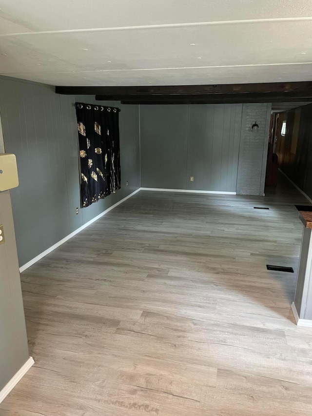 empty room with wood walls and light hardwood / wood-style flooring