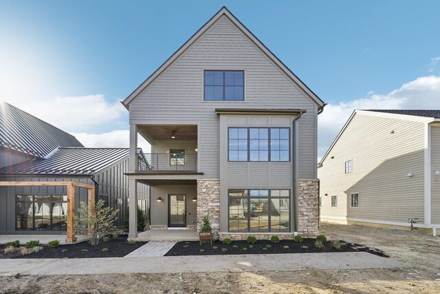 view of front of house featuring stone siding and a balcony