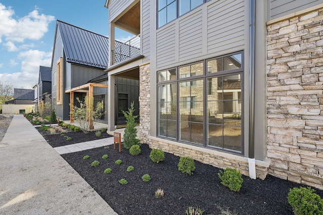 view of side of property with stone siding, a balcony, and metal roof