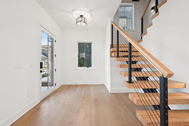 foyer with baseboards, stairs, and wood-type flooring