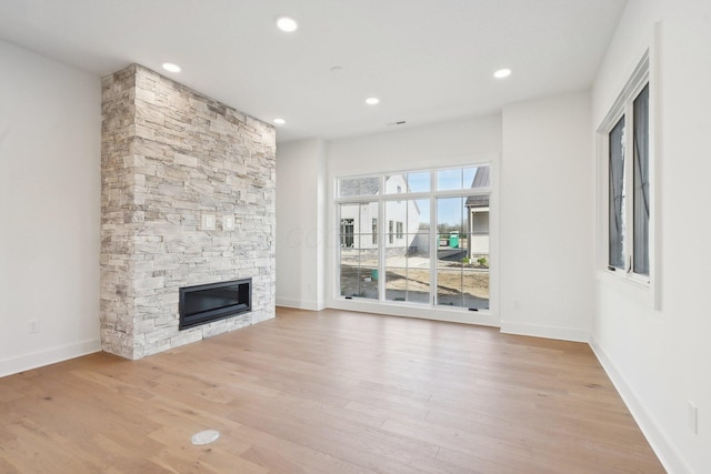 unfurnished living room with a fireplace, light wood finished floors, baseboards, and recessed lighting