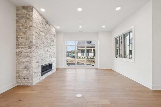 unfurnished living room featuring recessed lighting, a stone fireplace, and baseboards