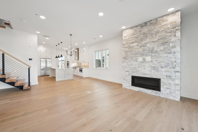unfurnished living room featuring light wood finished floors, baseboards, recessed lighting, and stairs