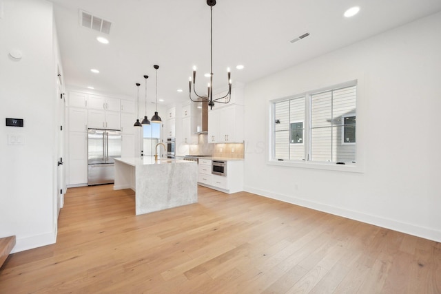 kitchen with white cabinets, stainless steel appliances, light wood-type flooring, visible vents, and light countertops