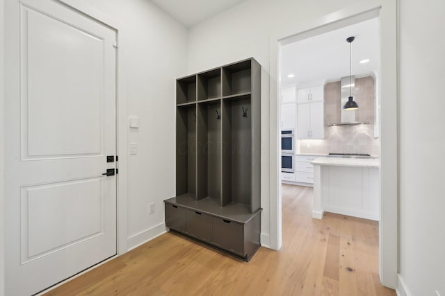 mudroom with baseboards, recessed lighting, and light wood-style floors