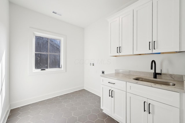 kitchen with white cabinets, baseboards, a sink, and light countertops