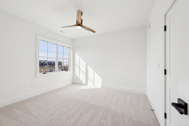 carpeted spare room featuring visible vents, a ceiling fan, and baseboards